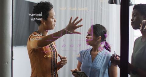 Businesswomen Collaborating on Ideas at Transparent Board