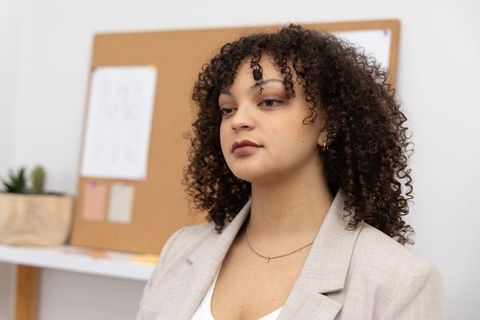 African american professional woman wearing beige blazer posing calmly in minimal workspace