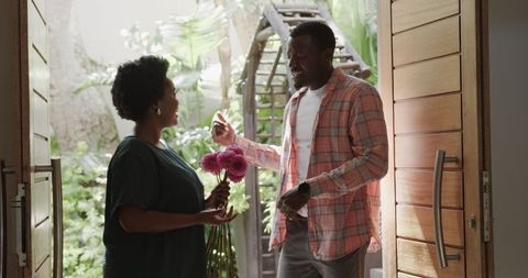 Couple sharing flowers at home entrance with love
