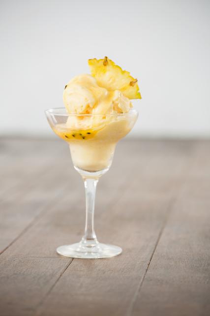 Refreshing pineapple sorbet served in an elegant glass with a decorative pineapple wedge. Perfect for use in food and beverage marketing, menus, recipe blogs, and gourmet dessert promotions.