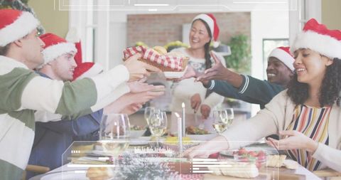 Friends exchanging holiday gift basket around festive dining table wearing Santa hats