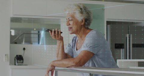 Elderly woman interacting with holographic smartphone technology at home