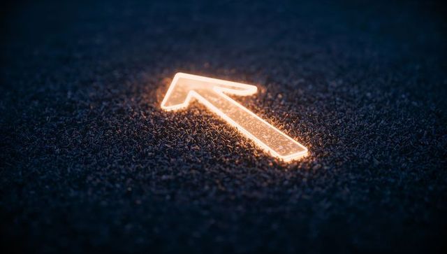 Glowing amber arrow neon pointer on dark granular surface casting warm light futuristic