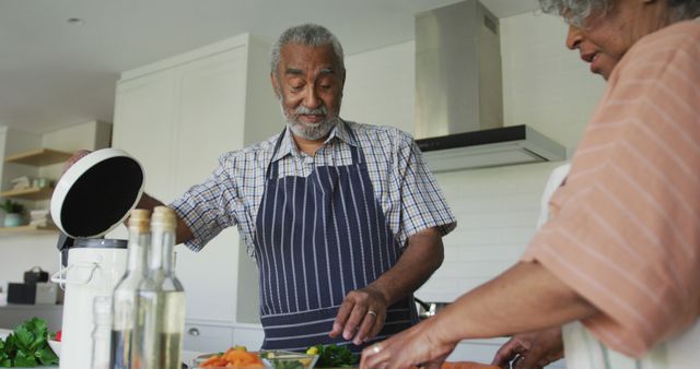 Elderly couple prepping ingredients and cooking together in modern kitchen. Ideal usage for promotions on healthy aging, home cooking, family bonding, active lifestyle for seniors, and culinary trends for older demographic.