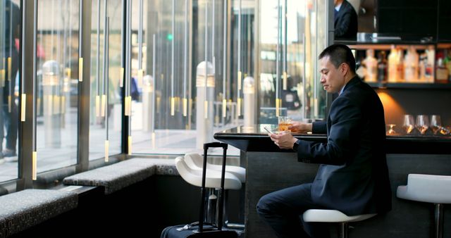 Businessman in Hotel Lounge Checking Phone and Drinking Whiskey - Download Free Stock Images Pikwizard.com