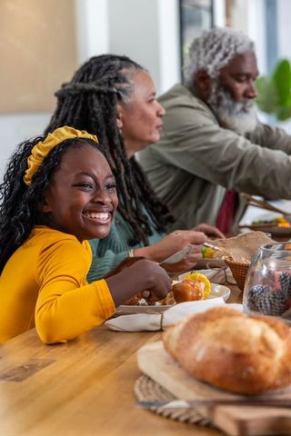 Smiling african american girl enjoying intergenerational family dinner at kitchen table