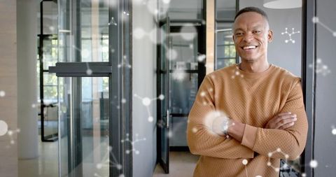 Confident professional smiling in modern office corridor with glass partitions and daylight