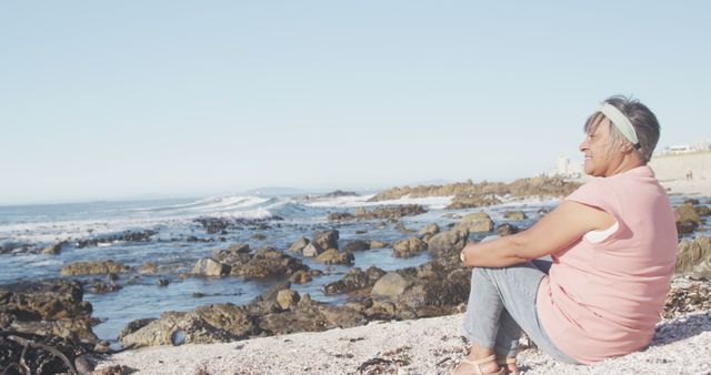 Serene Elderly Woman Reflecting on Rocky Shore in Best Light - Download Free Stock Images Pikwizard.com