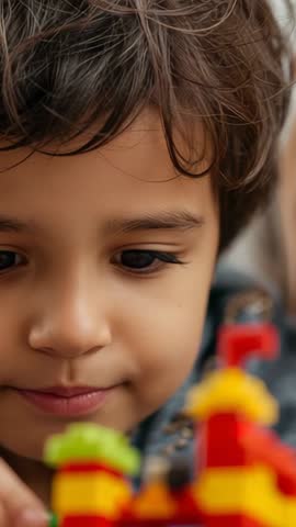 Vertical video: preschool boy building colorful block tower, focused creative play