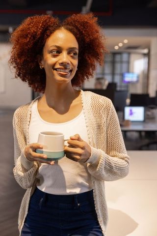 Smiling Woman Enjoying Coffee in Modern Office Setting