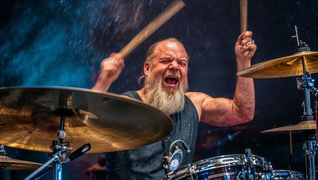 Bearded senior rock drummer delivering explosive live performance with dynamic energy
