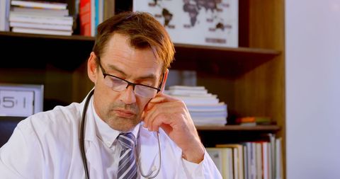 Serious Doctor Working at Desk in Medical Office