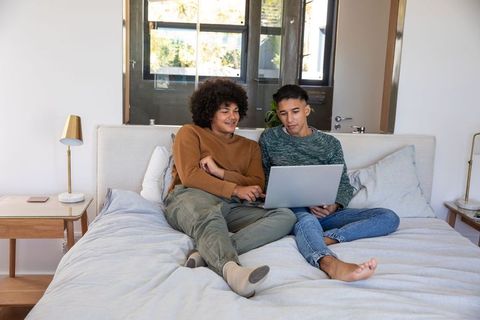 Couple Relaxing Together on Bed Using Laptop at Home