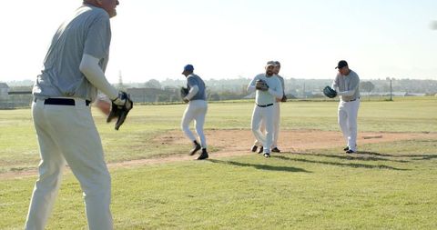 Baseball Team Warming Up on Sunny Grass Field Players Practicing Throws Fielding Drills