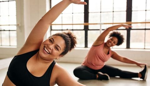 Joyful women stretching in bright studio for group fitness warm-up and flexibility training