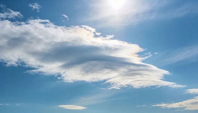 Lenticular Cloud Sculpting Bright Blue Sky with Sunlit Iridescent Hues and Cirrus Veil