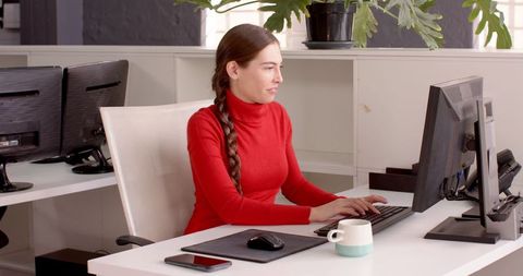 Woman Engaged with Technology at Desk in Modern Office Setting