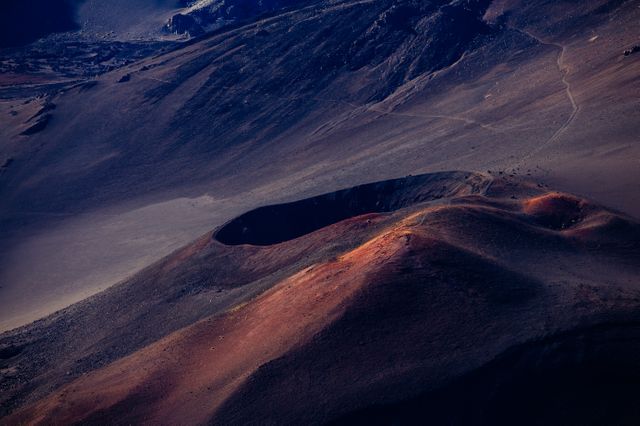 Aerial view of a volcanic landscape with rugged terrain at sunrise, highlighting the crater and colorful earth formations. Perfect for use in nature documentaries, geology educational materials, travel advertisements, or any content related to Earth's natural wonders and landscapes.