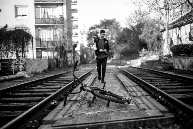 Man Walking on Railway Tracks with Fallen Bicycle in Urban Setting - Download Free Stock Images Pikwizard.com