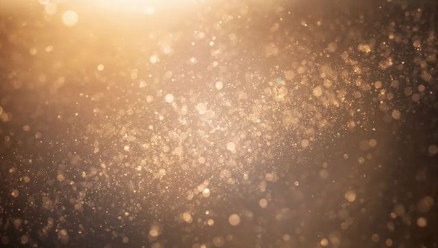 Golden Glitter Bokeh Background with Shimmering Particles and Warm Backlit Lens Flare
