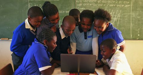 Excited Students Collaborating on Laptop in Classroom