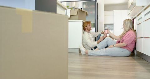 Happy couple enjoying coffee amidst moving boxes in new home