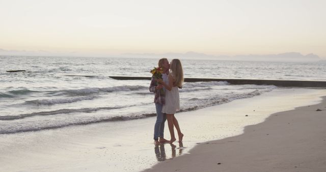 Romantic caucasian couple embracing and kissing on beach at sunset. Vacations, romance, love nature and relaxation, unalterned.