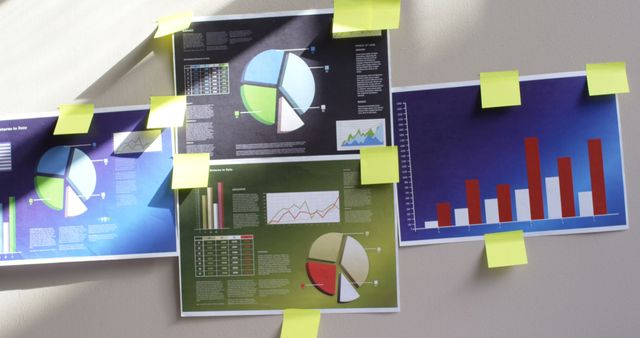 Charts and graphs are pinned on a wall, with copy space. Office setting reflects a brainstorming session or project planning.