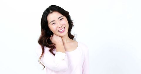 Cheerful asian woman smiling in studio with white background