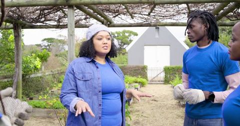 Leading volunteer team in community garden under pergola coordinating planting