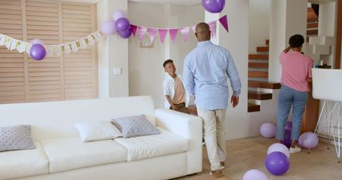African american family decorating living room with purple balloons celebrating birthday