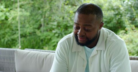 African american man relaxing on wicker sofa outdoors surrounded by lush green garden