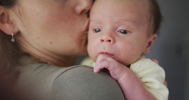 Mother gently holds and kisses her newborn baby, emphasizing bonding and affection. Perfect for use in parenting blogs, family health articles, maternal care advertisements, or stock photos for websites focusing on motherhood and family life.