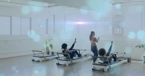 Pilates reformer class with instructor guiding women on core exercises in bright studio