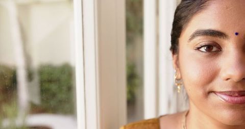 Smiling Woman with Traditional Indian Bindi by Sunlit Window