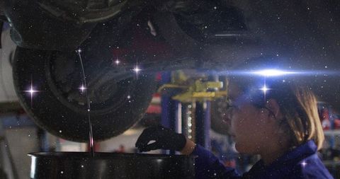 Female technician guiding engine oil into drum under car lift with cosmic star overlay