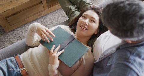Happy Couple Relaxing Together With Book at Home