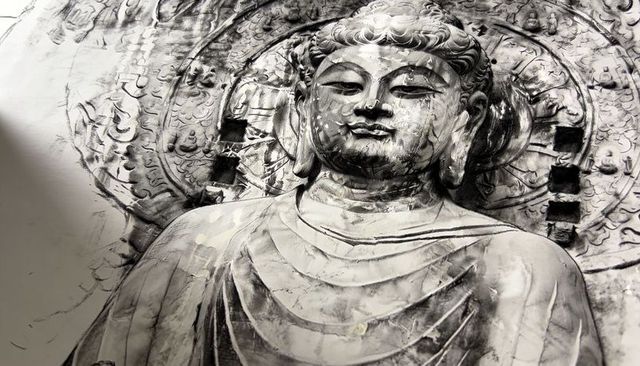 Weathered stone buddha bas-relief close-up with ornate halo and serene expression monochrome