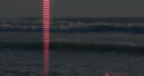 Luminous Red Beam Reflecting on Ocean Waves at Night