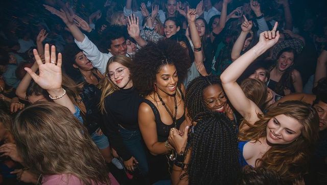 Crowded nightclub dance floor featuring black woman leading joyful, energetic celebration