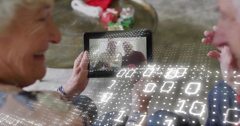 Senior couple video calling family on tablet with santa hats and digital overlay