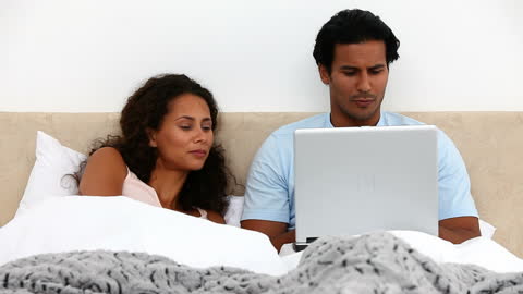 Couple Relaxing with Laptop in Cozy Bedroom Environment