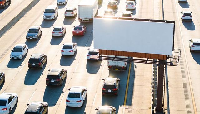 Blank billboard towering over busy freeway during golden hour for advertising mockups