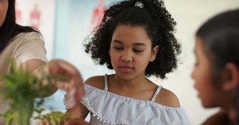 African american girl tending houseplants with family member indoor plant care and bonding