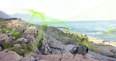 Hiker Enjoying Coastal Rocky Shoreline with Backpack and Gear