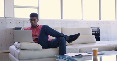 Focused Young Professional Using Laptop in Modern Office Lobby