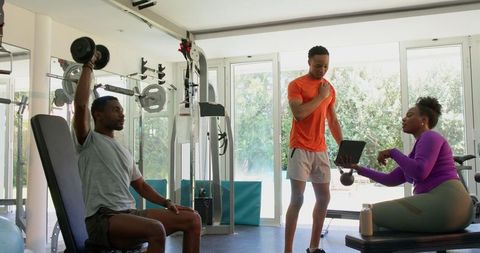 Young Couple Working Out in Home Gym with Weights and Tablet