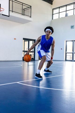 Dynamic Athlete Dribbling Basketball in Gymnasium Setting