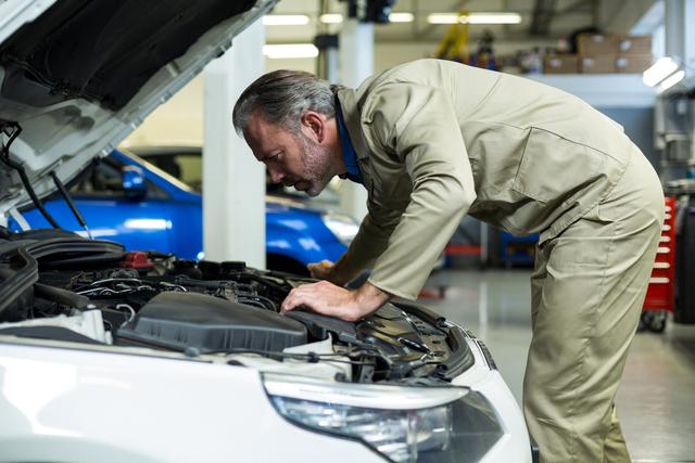 Mechanic examining automobile car engine in repair garage