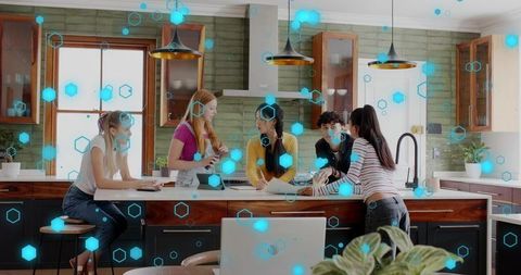 Young team collaborating around modern kitchen island with laptop and digital network overlay